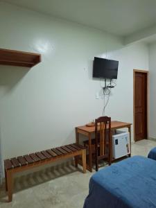 ein Zimmer mit einem Schreibtisch, einer Bank und einem Fernseher in der Unterkunft Pousada Banzeiro Marajó in Soure + 14 Fotos