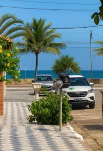 un parking avec des voitures et un oiseau sur un horodateur dans l'établissement Casa Pé na Areia Centro de Mongaguá, à Mongaguá
