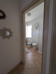 ein Bad mit einem WC und einem Wandspiegel in der Unterkunft Sea view house, private parking, WiFi in Badesi