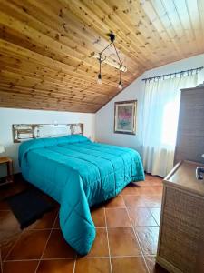 ein großes blaues Bett in einem Zimmer mit Holzdecke in der Unterkunft Casa Zuzu in Ovindoli