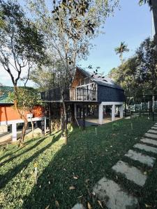 a house with a balcony and a grass yard at Hayashi Resort in Meppādi