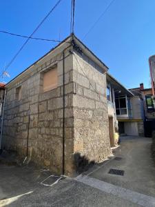 een gebouw met een stenen muur naast een straat bij A Casiña de Coles in Gustey