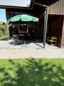 a patio with a grill and a green umbrella at Charmant Studio in Mattsee +4 photos