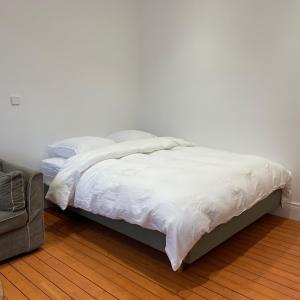 Una cama con sábanas blancas y almohadas en un dormitorio. en Studio La cabine, en Wimereux