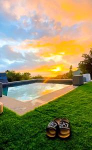 Blackhouse jacuzzi piscina في بونتيفيدرا: زوج من الأحذية موضوع على العشب بجوار حمام سباحة