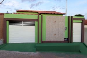 two white garage doors on a green building at Casa completa de temporada- ReFÚGIO in Piranhas