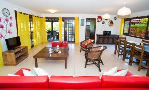 a living room with a red couch and a tv at Casa Giada Eleganza tropicale nel cuore di Praia do Forte in Praia do Forte