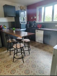 Una cocina con una mesa de madera y algunas sillas. en Chambre a 5 min de center parc, en Les-Trois-Moutiers