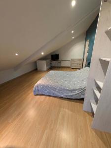 Un dormitorio con una cama y suelo de madera. en Chambre a 5 min de Center Parc bois aux daims, en Les-Trois-Moutiers