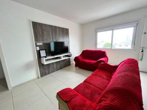 a living room with a red couch and a red chair at Residencial Lazzari Apto 302 in Arroio do Sal