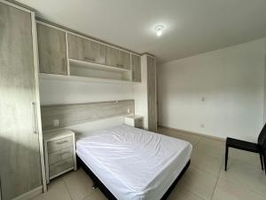 a bedroom with a white bed and wooden cabinets at Residencial Lazzari Apto 302 in Arroio do Sal