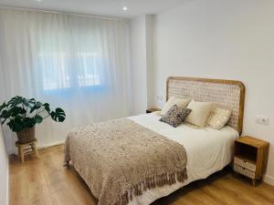 a bedroom with a large bed and a potted plant at RÍA LIVING - Mar 03 in Cee