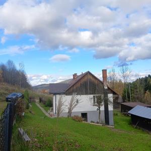 a white house in a field with a fence at Dom w górach Zacisze lasu in Sucha Beskidzka