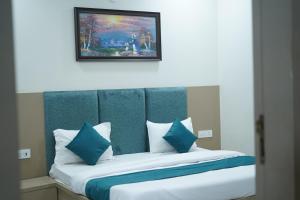 een bed met blauwe en witte kussens en een schilderij bij Hotel Shri Radha Sneh 500 Mtrs From Shri Krishna Janma Bhumi Mathura in Mathura