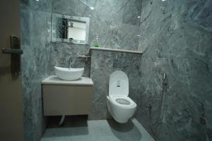 een badkamer met een toilet, een wastafel en een spiegel bij Hotel Shri Radha Sneh 500 Mtrs From Shri Krishna Janma Bhumi Mathura in Mathura +17 foto's