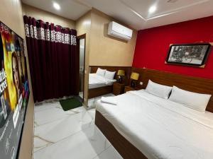 a bedroom with two beds and a red wall at hotel Elites Residency in city center , iqbal town in Lahore