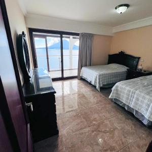 Una habitación de hotel con dos camas y una gran ventana. en Penthouse con vistas espectaculares del Lago de Atitlán, en Panajachel 23 fotos más