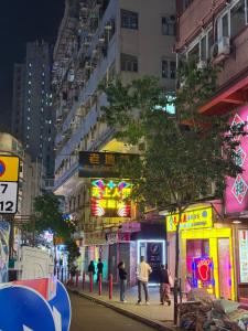 香港市中心九龍尖沙咀民宿公寓a في هونغ كونغ: شارع المدينة بالليل فيه ناس تمشي على الرصيف