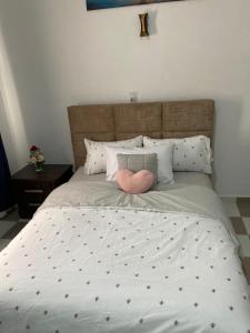 a large bed with a pink heart pillow on it at EdenRose Guest House in Kwabenya
