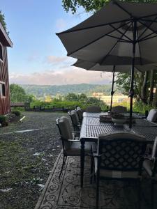 een tafel met stoelen en een parasol op een terras bij The Allen House in North Adams
