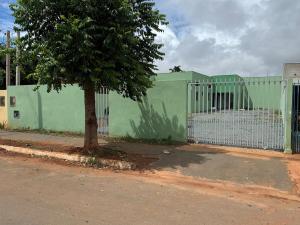 a green fence with a tree in front of it at Casa aconchegante com 02 quartos climatizados in Nova Mutum +1 photo