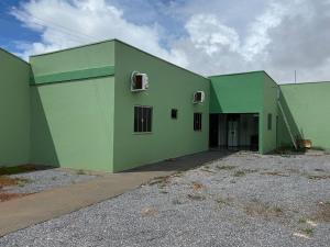 a large green building with a garage at Casa aconchegante com 02 quartos climatizados in Nova Mutum