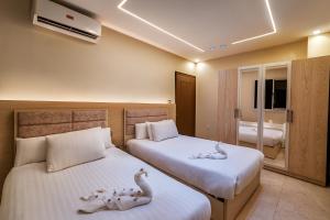 Dos camas en una habitación de hotel con cisnes. en Nisut Pyramids Hotel, en El Cairo