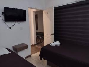 a bedroom with a bed and a flat screen tv at Hotel Begrand in Tapachula