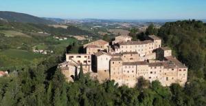 un grande castello in cima a una collina con alberi di Mia Piccola Casina ad Arcevia