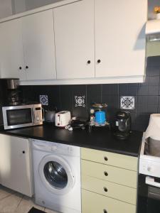 a kitchen with a washing machine and a microwave at jim villa family apartment with private yard andravida-kyllini in Andravída