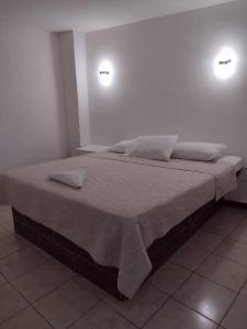 a large bed in a room with two lights at Hotel Begrand in Tapachula