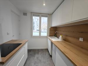 a kitchen with white cabinets and a sink and a window at Cozy T3 & Parking - Moulin à Vent in Perpignan