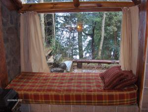 ein Bett in einem Zimmer mit einem großen Fenster in der Unterkunft Cabañas Kalfulafquen in Villa La Angostura