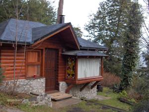 eine Blockhütte mit einer Veranda und einem Fenster in der Unterkunft Cabañas Kalfulafquen in Villa La Angostura