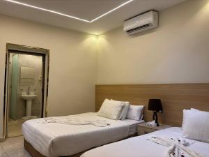 Una habitación de hotel con dos camas y un baño. en Nisut Pyramids Hotel, en El Cairo 4 fotos más
