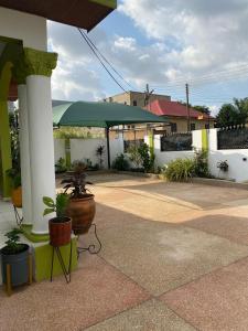 a patio with a green umbrella and potted plants at EdenRose Guest House in Kwabenya