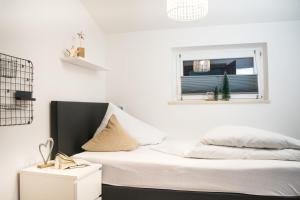 a white bedroom with a bed and a window at Dili Appartement in Altenmarkt im Pongau