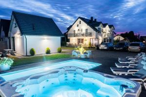 a swimming pool in front of a house at Cichy Domek Karwia - Apartamenty - Basen, Jacuzzi, Sauna in Karwia