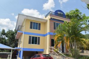 ein gelbes Haus mit einem davor geparkten roten Auto in der Unterkunft Finca el Paraiso Casa Loma, Tena in Tena