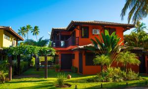 an orange house with palm trees in front of it at Casa Giada in Praia do Forte