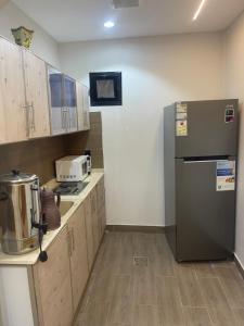 Una cocina con refrigerador de acero inoxidable y gabinetes de madera. en شاليه نخله, en Al Ula