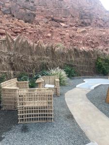 Un patio con sillas de mimbre y una pasarela. en شاليه نخله, en Al Ula