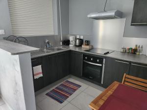 una cocina con fregadero y estufa horno superior en L'orchidée de kinabalu, en Cabassou