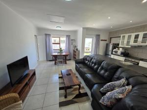 a living room with a black leather couch and a table at Alvera in Strand