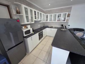 a kitchen with white cabinets and a black counter top at Alvera in Strand +2 photos