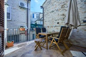 einen Tisch und Stühle auf einem Balkon mit Sonnenschirm in der Unterkunft Casa Vicolo TerminIO in Fermo