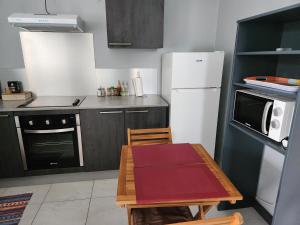 Una cocina con una mesa y un refrigerador blanco. en L'orchidée de kinabalu, en Cabassou
