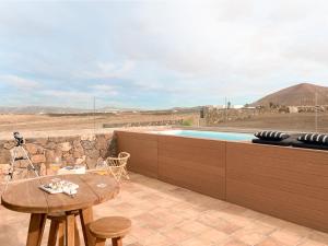 Un patio con una mesa y una piscina. en Canaryislandshost l The Sky Suites, en Tinajo