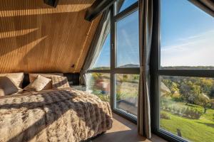 a bedroom with a bed and large windows at LoveNest Hungary in Győrújbarát