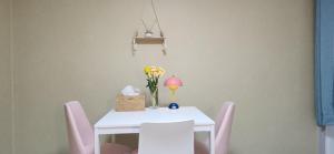 a white table with pink chairs and a vase of flowers at 베델하우스 Bethel House in Seoul